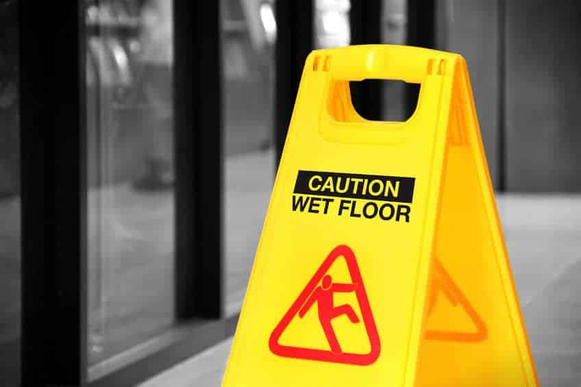 bright yellow caution sign of wet floor in a hallway. conceptual image with isolated color over black and white background