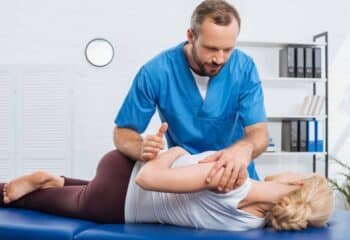 chiropractor adjusting a patient's back while in their office