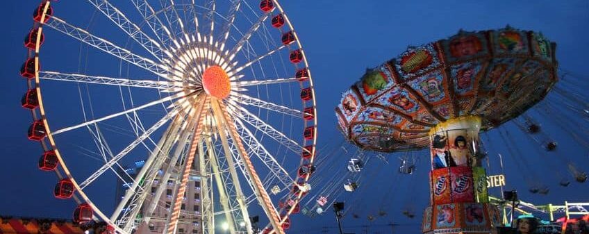a carnival with a ferris wheel and swing ride lit up