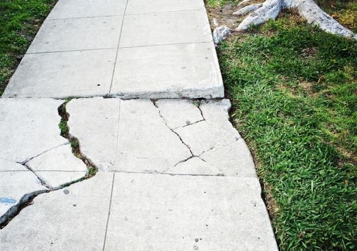 large crack in an uneven sidewalk