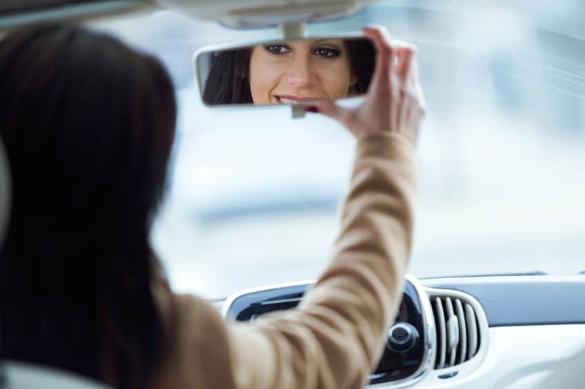 person fixing rear view mirror of the car while driving